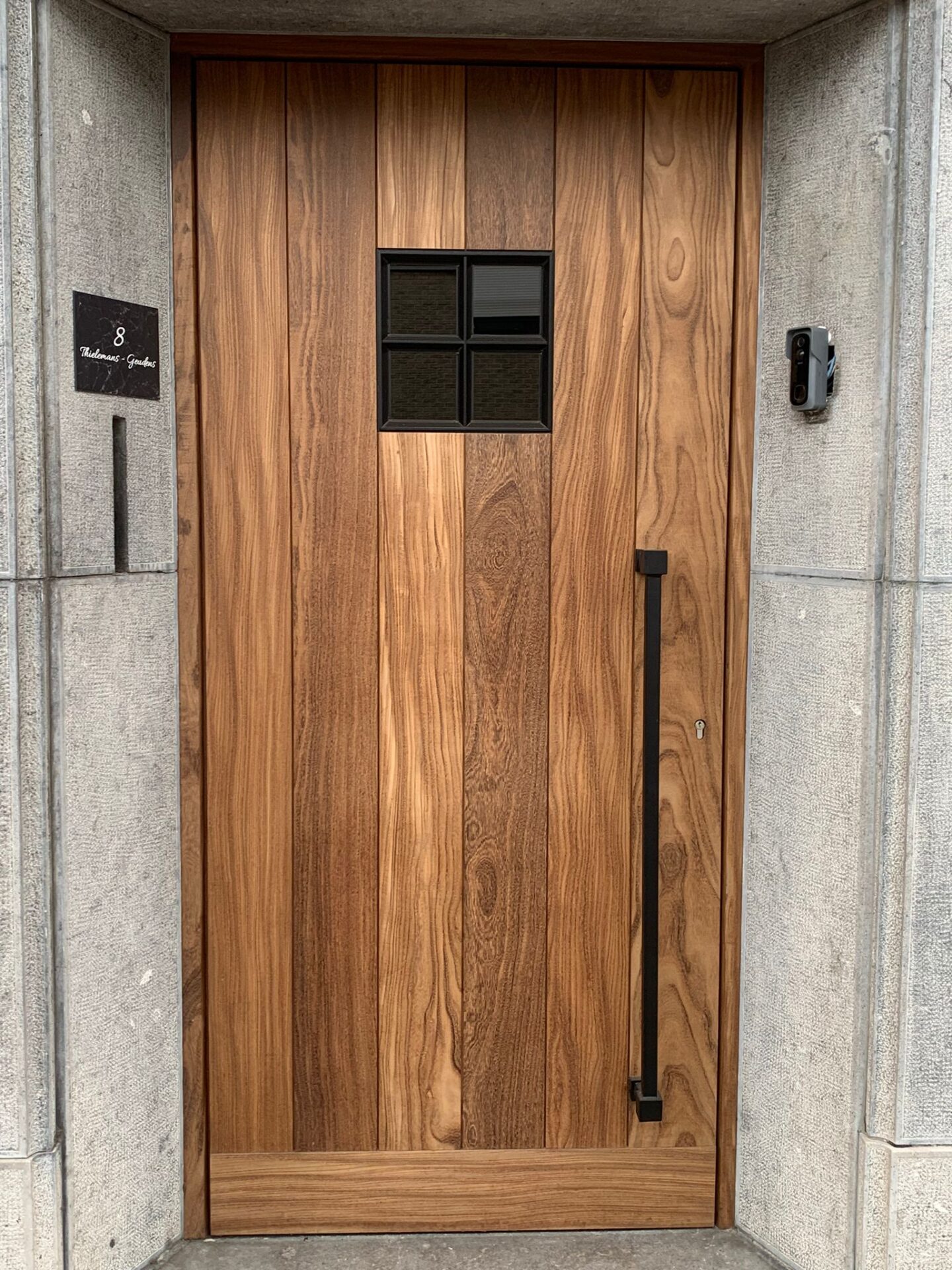 Houten deur met zwart deurbeslag en huisnummer 8